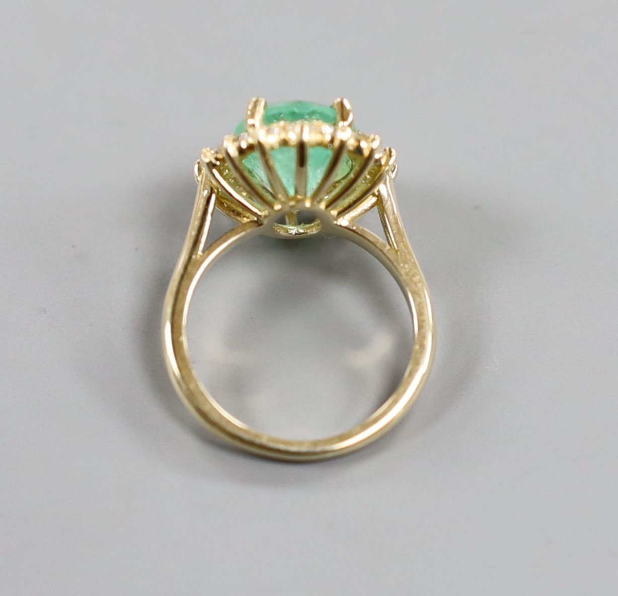 A modern 14k yellow metal, emerald and diamond set oval cluster ring, size M, gross weight 5.9 grams, with accompanying G.A.S. certificate dated 6/7/2016 estimating the emerald to weigh approximately 4.67ct.